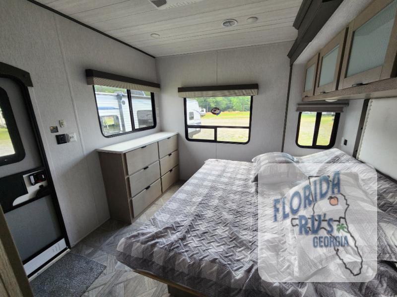 Forest River RV Salem Villa Series 40FDEN interior bedroom with an exterior door, dresser, and overhead storage